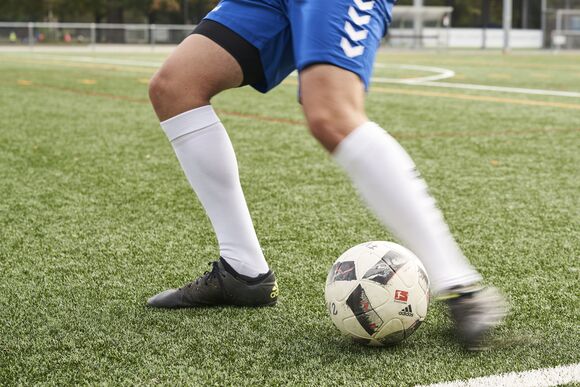 Man sieht die Beine eines Fu&szlig;ballers mit einem Fu&szlig;ball 