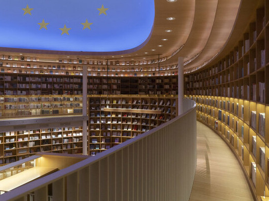 Innenansicht einer modernen Bibliothek in Europa mit geschwungenem Bücherregal und Decke mit Europaflagge | Foto: © T_Tide/Pixabay